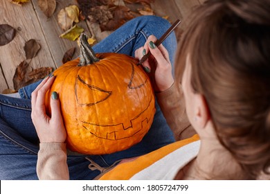 Woman painting pumpkin face and making jack latern for Halloween