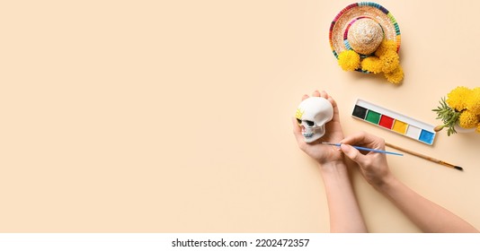 Woman Painting Skull For Mexico's Day Of The Dead (El Dia De Muertos) On Beige Background With Space For Text, Top View