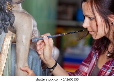 Woman painting statue with paintbrush in workshop - Powered by Shutterstock