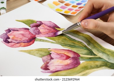 Woman painting tulips in sketchbook at table, closeup - Powered by Shutterstock