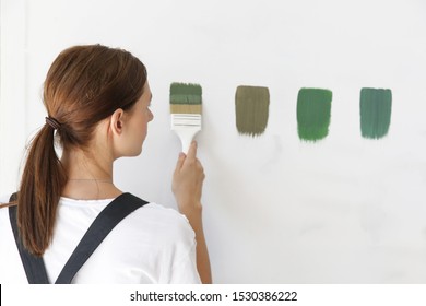 Woman Is Painting The Wall With Adifferent Color Swatches. Process Of Choosing The Right Color For The Wall, DIY Home Improvement Concept.	