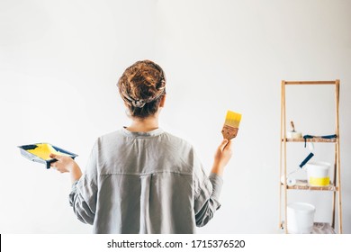 Woman painting wall. Rear view of woman with paint brush painting wall. Repair and house renovation concept. - Powered by Shutterstock