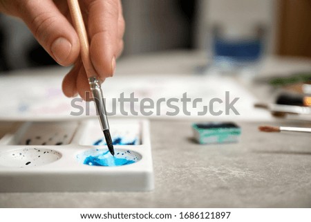 Woman painting with watercolor at grey stone table, closeup. Space for text