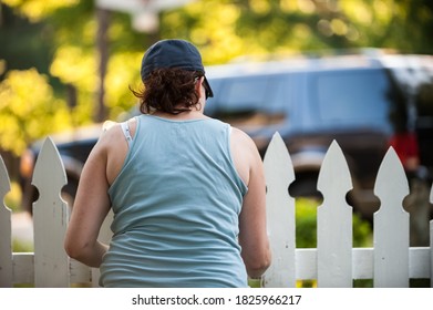 Woman Painting A White Picket Fence From Behind