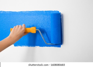 Woman Painting White Wall With Blue Dye, Closeup. Interior Renovation