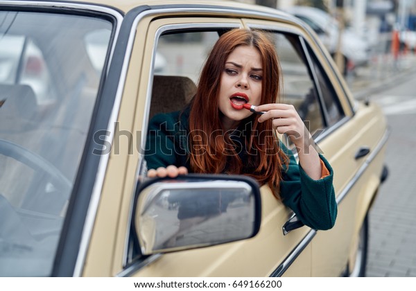 Woman paints lips with red lipstick,
woman paints lips in car                              
