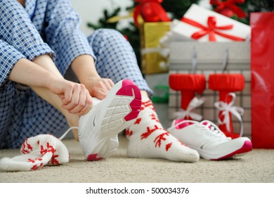 Woman In Pajamas Ties The Laces Of Athletic Shoes. Christmas Present. Birthday Present.