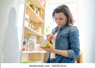 Woman in pantry with groceries, wooden rack for storing food in the kitchen.