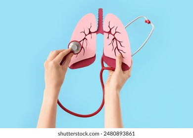 Woman with paper lungs and stethoscope on blue background - Powered by Shutterstock