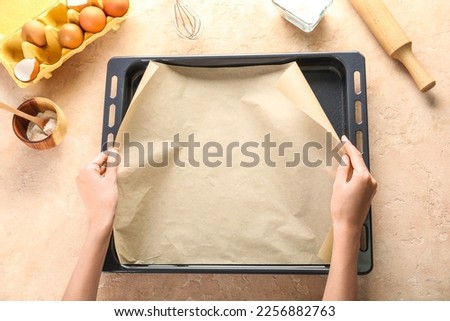 Woman with parchment paper, baking tray and ingredients on beige background ストックフォト © 
