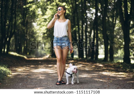 Woman in park with french bulldog talking on the phone