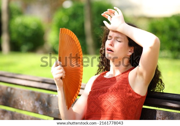 Woman in a park\
suffering heat stroke\
fanning