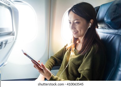 Woman Passenger In Airplane Using Cellphone With Earphone