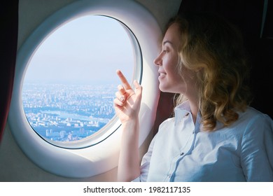 woman passenger of the plane with interest looks at the city below outside the window - Powered by Shutterstock