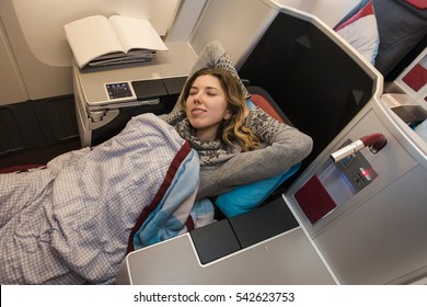 Woman Passenger Sleeping At The Business Class Of Airplane In Comfortable Single Seat. Flight At First Class Plane