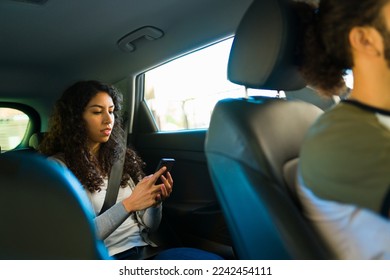 Woman passenger texting on the smartphone in the car while taking a trip on a ride share service  - Shutterstock ID 2242454111