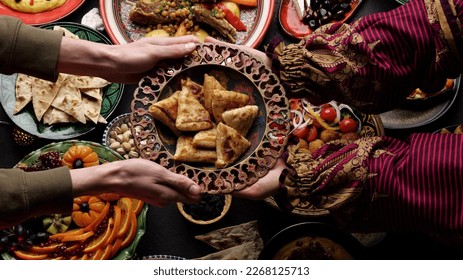 A woman passes a plate of fried samosa to a man. Dinner together. Authentic local homemade traditional meals in traditional dishes - Shutterstock ID 2268125713