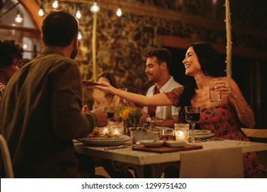 Woman Passing Food To Friends At Dinner Party Outdoors. Millennials Having Dinner Together Outdoors.