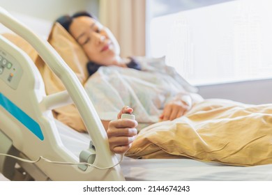 Woman patient holding emergency call button while lying in hospital  bed