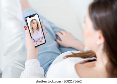 Woman patient listens to careful lady psychologist advice at videocall via mobile phone sitting on sofa in living room close view - Powered by Shutterstock