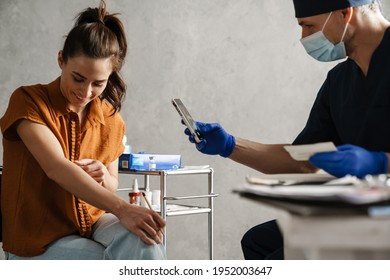 Woman Patient And Man Doctor Sitting In The Cabinet During Medical Examination, Doctor Taking Picture