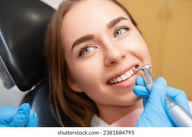 Woman patient sitting in medical chair during teeth grinding procedure. - Powered by Shutterstock