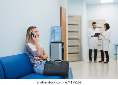 Woman Patient In Speaking At The Mobile Phone In Hospital Waiting Room.