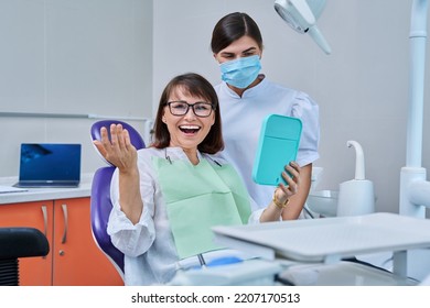 Woman patient together with dentist, patient sitting in dental chair looking at mirror - Shutterstock ID 2207170513