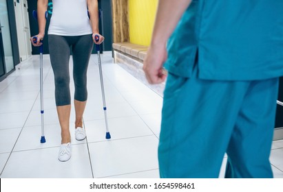 Woman patient using crutches for rehabilitation after injury. Physiotherapist assisting a patient. - Powered by Shutterstock