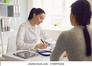 Woman patient visiting female doctor at clinic office. Medical work writes a prescription on a table in a hospital. - Shutterstock ID 1720976266