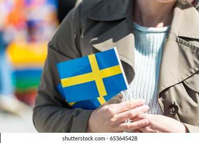 Woman as a patriot holding in his hand a paper flag of Sweden