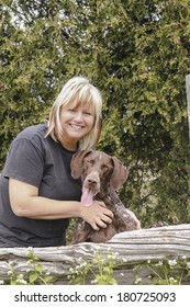 Woman Patting Dog Beside Fence