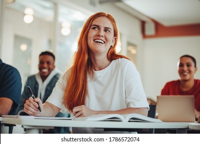 Woman paying attention in lecture. Female student listening to the teacher and smiling sitting in classroom. - Powered by Shutterstock