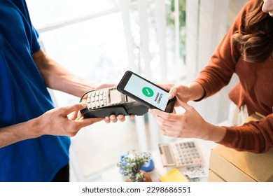 Woman paying bill through smartphone using contactless payment technology. Satisfied customer paying through mobile phone using NFC technology. Closeup hands of mobile payment at mobile handheld POS.