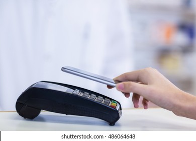 Woman paying bill through smartphone using NFC technology in pharmacy - Powered by Shutterstock