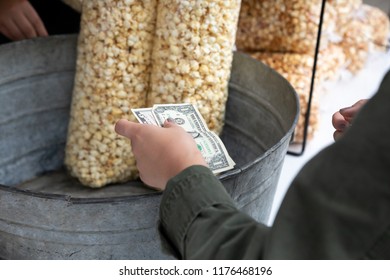 Woman Paying With Cash At An Outdoor Concession Stand, With Bags Of Kettle Corn In The Background And Space For Text On Top