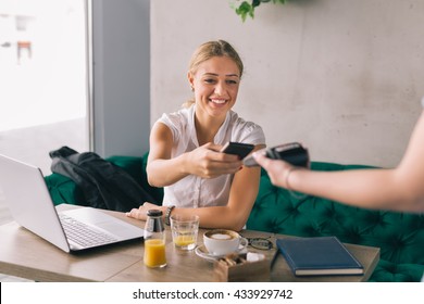 Woman Paying Contactless With Mobile Phone In Cafe Bar