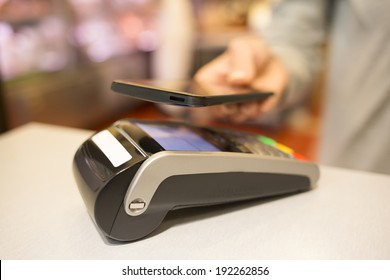 Woman Paying With NFC Technology On Mobile Phone, In Supermarket 