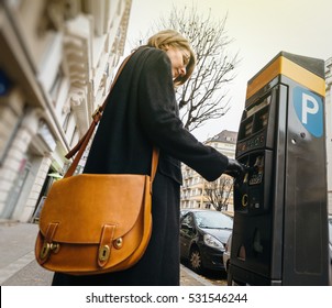 Woman paying for the parking at the teller machine in the city