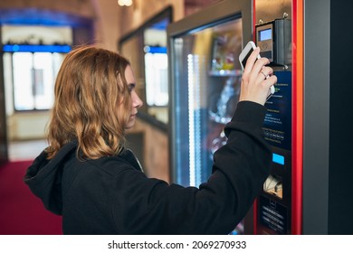 Woman paying for product at vending machine using contactless method of payment with mobile phone. Woman using new way of payments - Shutterstock ID 2069270933