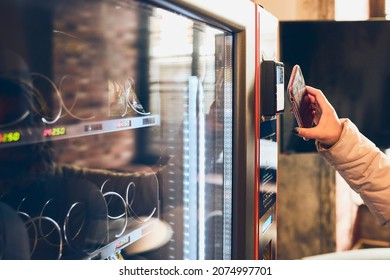 Woman paying for product at vending machine using contactless method of payment with mobile phone. Woman using new way of payments - Shutterstock ID 2074997701