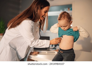 Woman pediatrician consulting kid and checking toddler boy in a home visit or in a hospital office. Female doctor examining little patient with a stethoscope and listening to his lungs and heartbeat. - Powered by Shutterstock