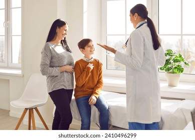 Woman pediatrician examining preteen boy patient who came with his mother. Cheerful doctor talking to mother and son at pediatric check up appointment in medical clinic. Children medical care concept - Powered by Shutterstock