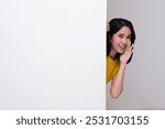 A woman peeking behind wall while whispering something with happy expression