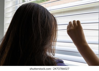 Woman peeking at neighborhood through window blinds from inside her home. - Powered by Shutterstock