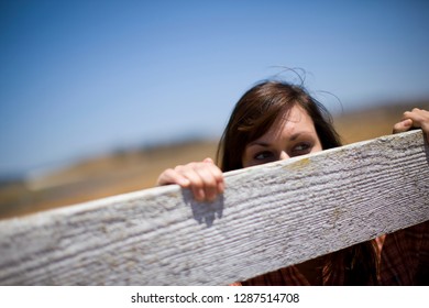 Woman Peeking Over Fence On Farm