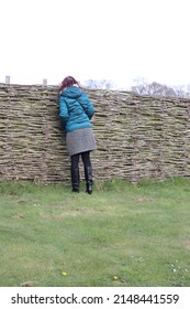 Woman peeks over a wattle fence
