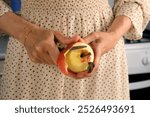 Woman peeling apple using knife cooking food dish on kitchen at home, hands close-up. Female housewife in dress preparing dish from apples. Culinary, cuisine, healthy eating, baking concept.