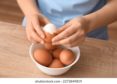 Woman peeling boiled egg at wooden table, closeup - Powered by Shutterstock