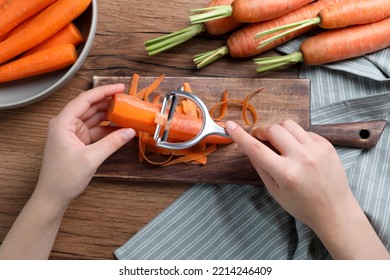 Woman peeling fresh carrot at wooden table, top view - Powered by Shutterstock